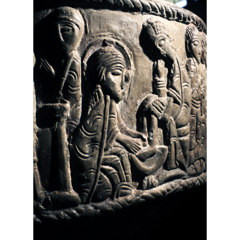 Christ Washing the feet of the Apostles. To the left and kneeling Christ in profile, haloed. To the right a figure is sitting down, both feet in a chalice like bowl. The person wears fancy hair, enriched robe. (additonal figue seated on a chair - may belong to this scene, although, the blessing gesture signifies that he is probably part of the next scene the Last Supper.