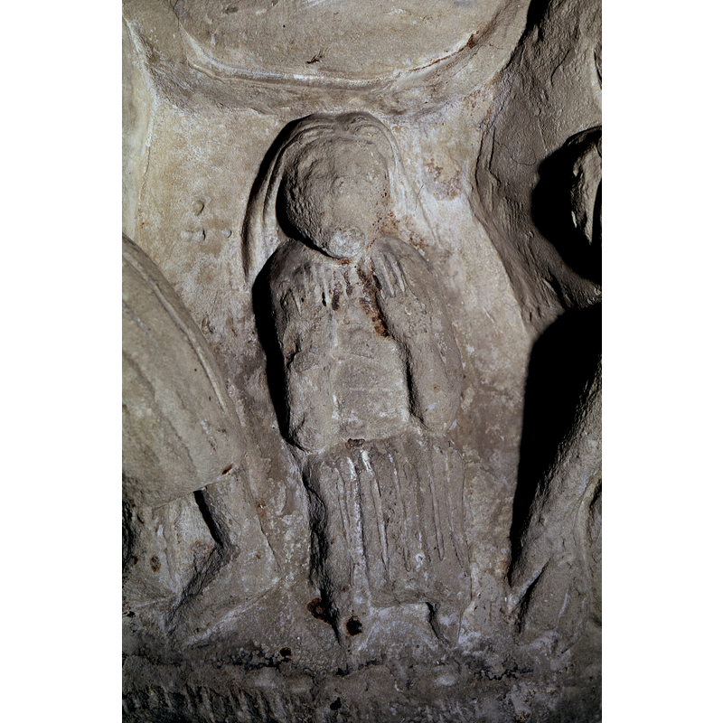 The long-haired figure is sitting, both hands raised in orant pose