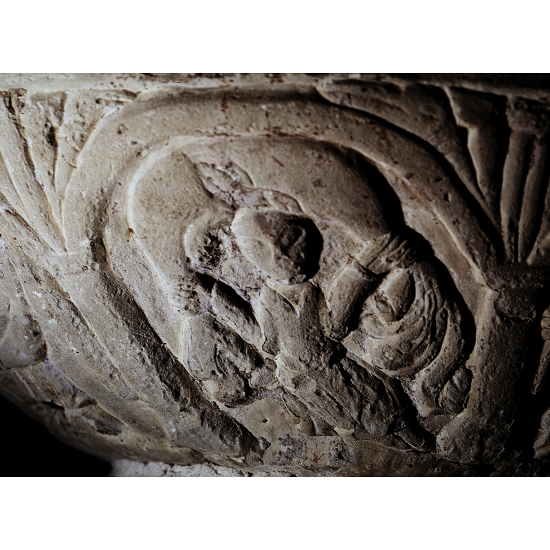 a figure, stands frontal, arms spread like the previous figures, holding a large cloth over the head and to the sides; the large cloth could be a serpent with head and extremities. The figure appears male and in a victorious pose. Roosval (1918) suggests the personification of night [="Personifikation der Nacht"]