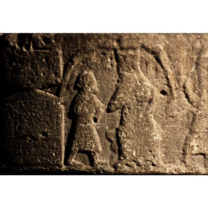 A soldier in profile on the left, next to an enthroned and crowned figure (Herod); to the right is asoldier holding an infant in his left hand; farther to the right is a tower with a cross on top.