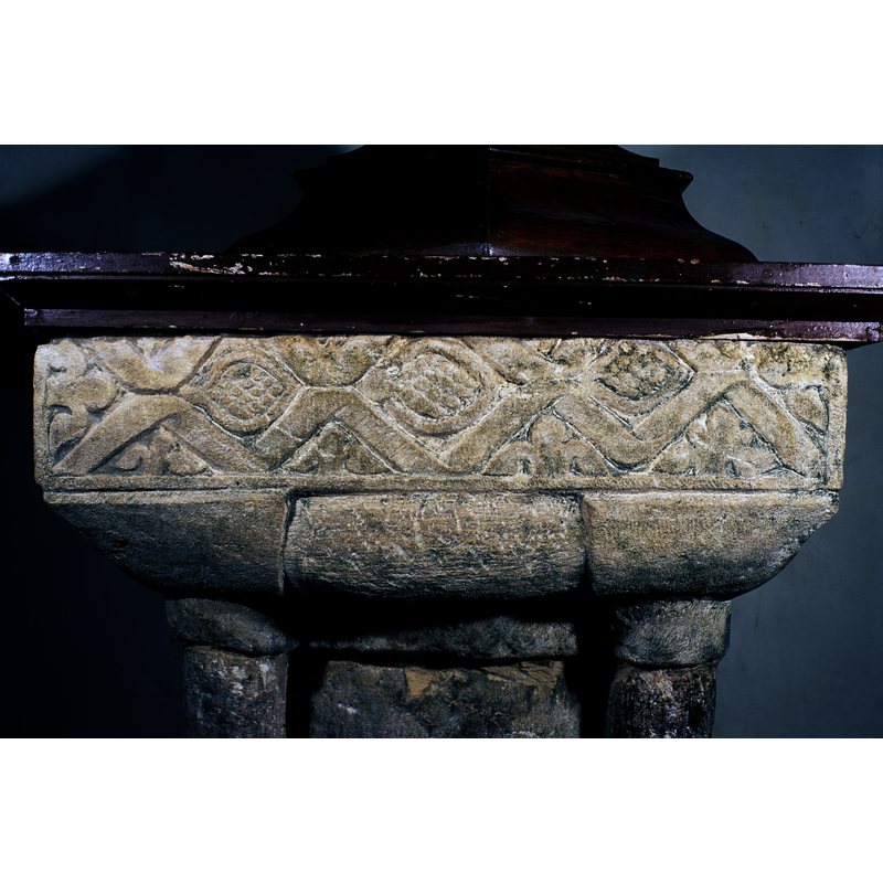 a schematic trefoiled plant or foliage in avery spandrel created by the ribbons; (Drake (2003: 344) describes them as "'piles' flanked by heads" but on close inspection they are definitely vegetal motifs; one or two may suggest the schematic rendering of a cherub